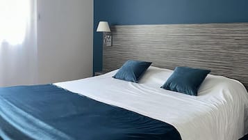 A hotel room with a bed, a nightstand, a lamp, and a view of the city.