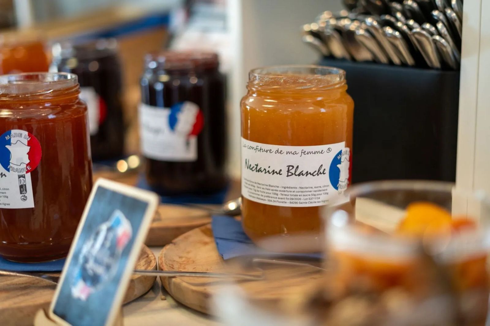 Una exhibición de varios frascos de miel y conservas, incluyendo un frasco etiquetado como 'Neetarine Blanche'.
