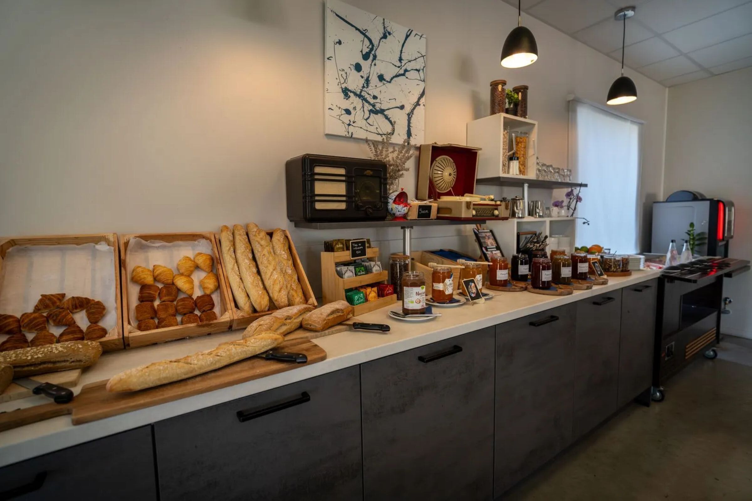 A kitchen counter with an assortment of breads, pastries, and jars of preserves.