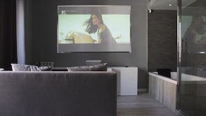 Un salon moderne doté d’un grand téléviseur à écran plat fixé au mur, d’un canapé gris et d’un design minimaliste.