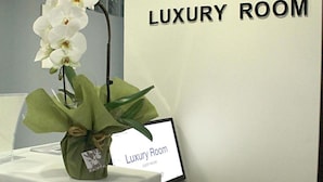 Une chambre de luxe avec une orchidée blanche posée sur une table, une pancarte indiquant « Chambre de luxe » et un petit tabouret en bois.