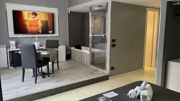 Une chambre d’hôtel moderne équipée d’un lit, d’un bureau, d’une chaise, d’une télévision et d’une salle de bain avec une douche en verre.