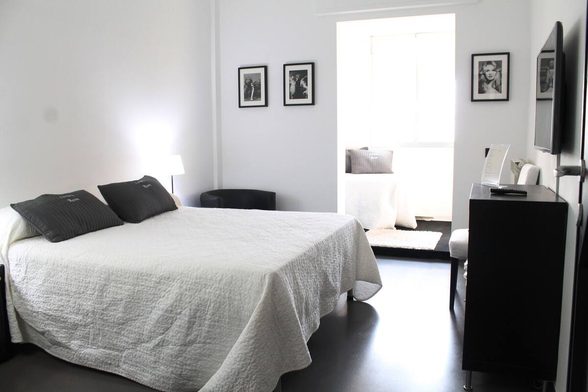 A hotel room with a bed, a desk, a chair, and a television.