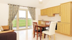 Een moderne keuken met houten kasten, een eettafel met stoelen en een groot raam met gordijnen.