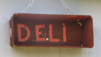 A wooden sign with the word "DELI" in red letters, hanging from a chain.