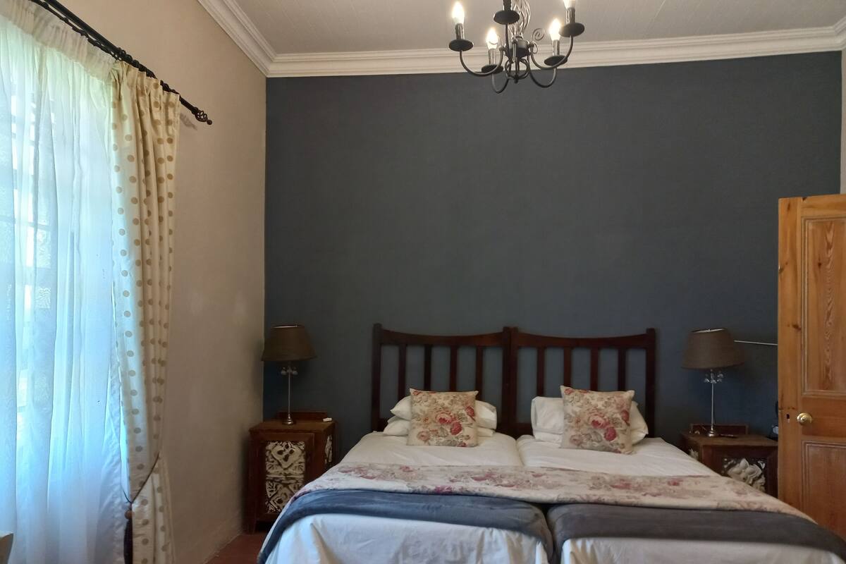 Quarto com cama, duas mesas de cabeceira, um candelabro e um guarda-roupa de madeira.