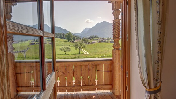 Un balcón de madera con vistas a un paisaje verde y montañas.