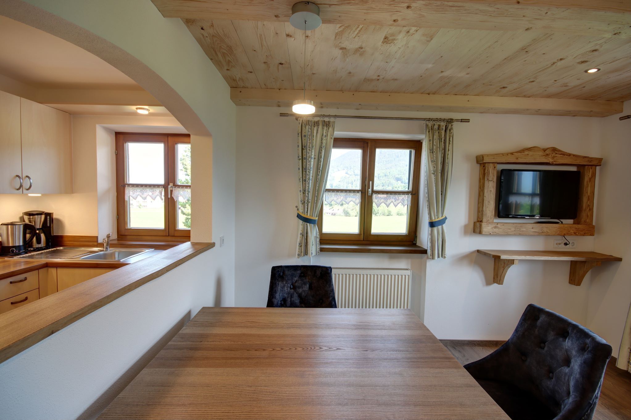 Une cuisine avec des meubles de rangement en bois, un évier et une table à manger avec des chaises.