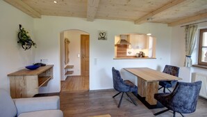 Un interior acogedor con una mesa de comedor de madera, dos sillas, un sofá y una zona de cocina con estufa integrada.
