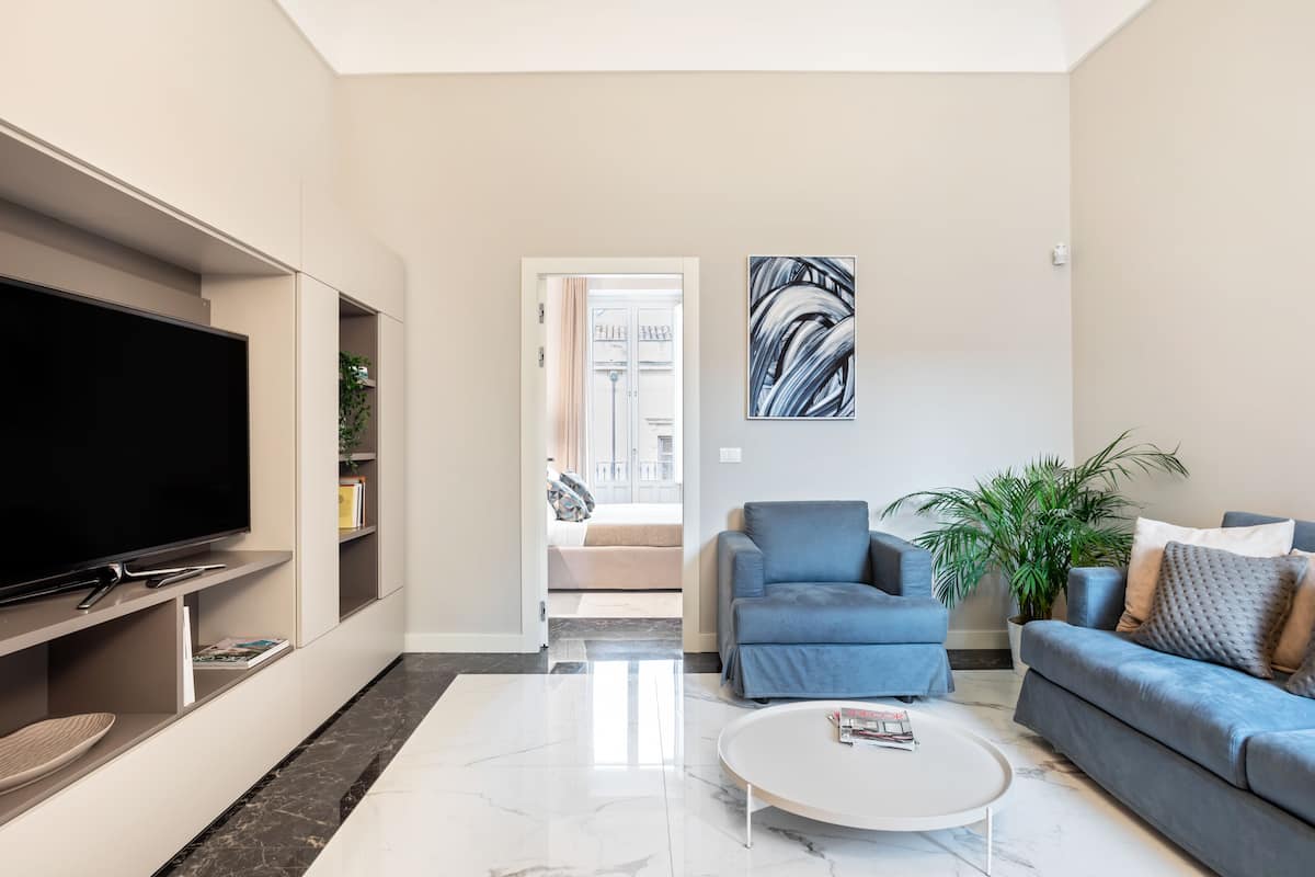 Un salon moderne avec un téléviseur à écran plat, une table basse blanche et deux canapés.