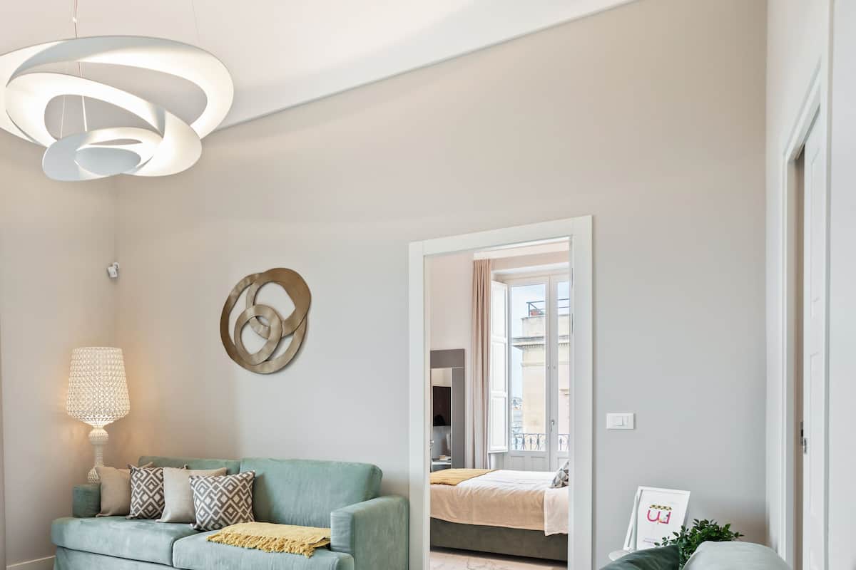 Un salon moderne avec un canapé, une lampe et une vue sur un immeuble par la fenêtre.