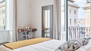 Une chambre d’hôtel avec un lit, un bureau et une vue sur la ville.