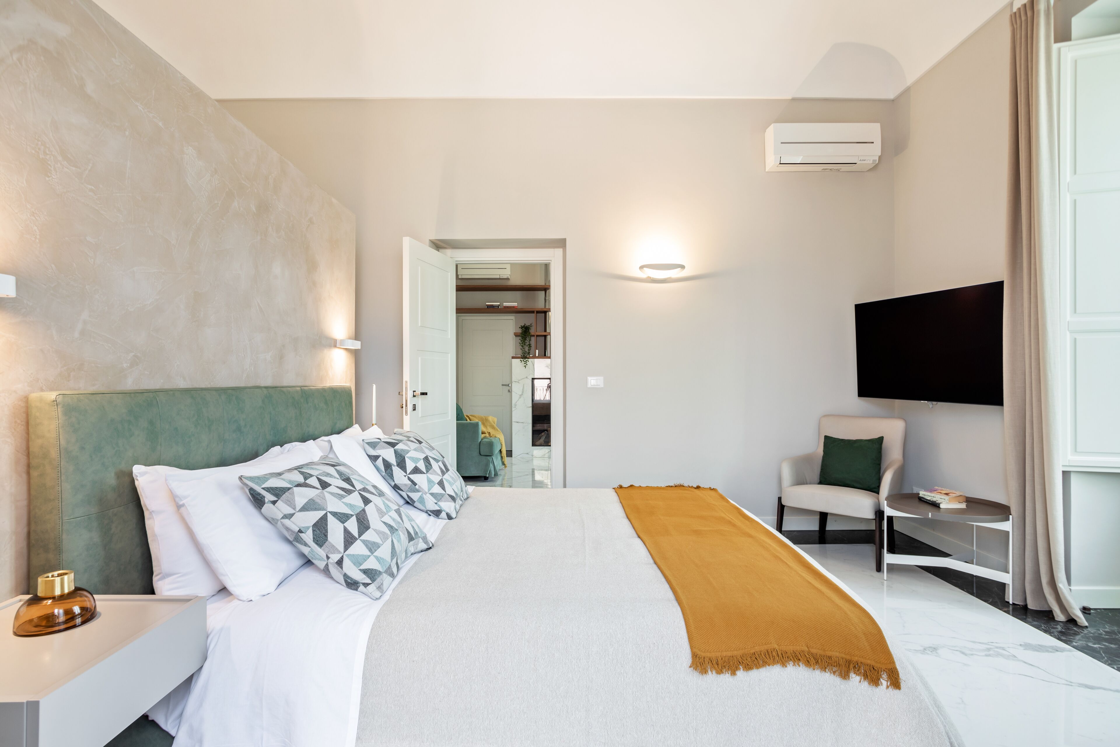 Ein modernes Hotelzimmer mit einem großen Bett, einem Flachbildfernseher, einer Sitzecke und einem sichtbaren Badezimmer.