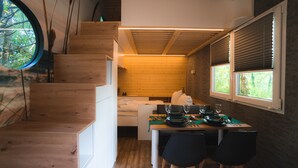 A wooden staircase leading to a bedroom with a window, a dining area with a table set for two, and a view of the outdoors. - Eurocamp Spreewaldtor (Märkische Heide)