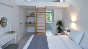Un dormitorio con baño elevado, una escalera de madera, una mesita de noche, una lámpara y una planta en maceta.