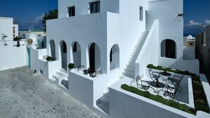 Un edificio blanco con escaleras, asientos exteriores y vista al mar.