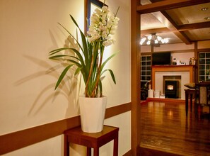 A room with a wooden floor, a white vase with a plant on a small table, and a fireplace in the background. - Altitude Madarao (Iiyama)