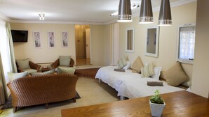 Ein Hotelzimmer mit einer Couch, einem Bett, einem Holztisch und einem an der Wand befestigten Fernseher.