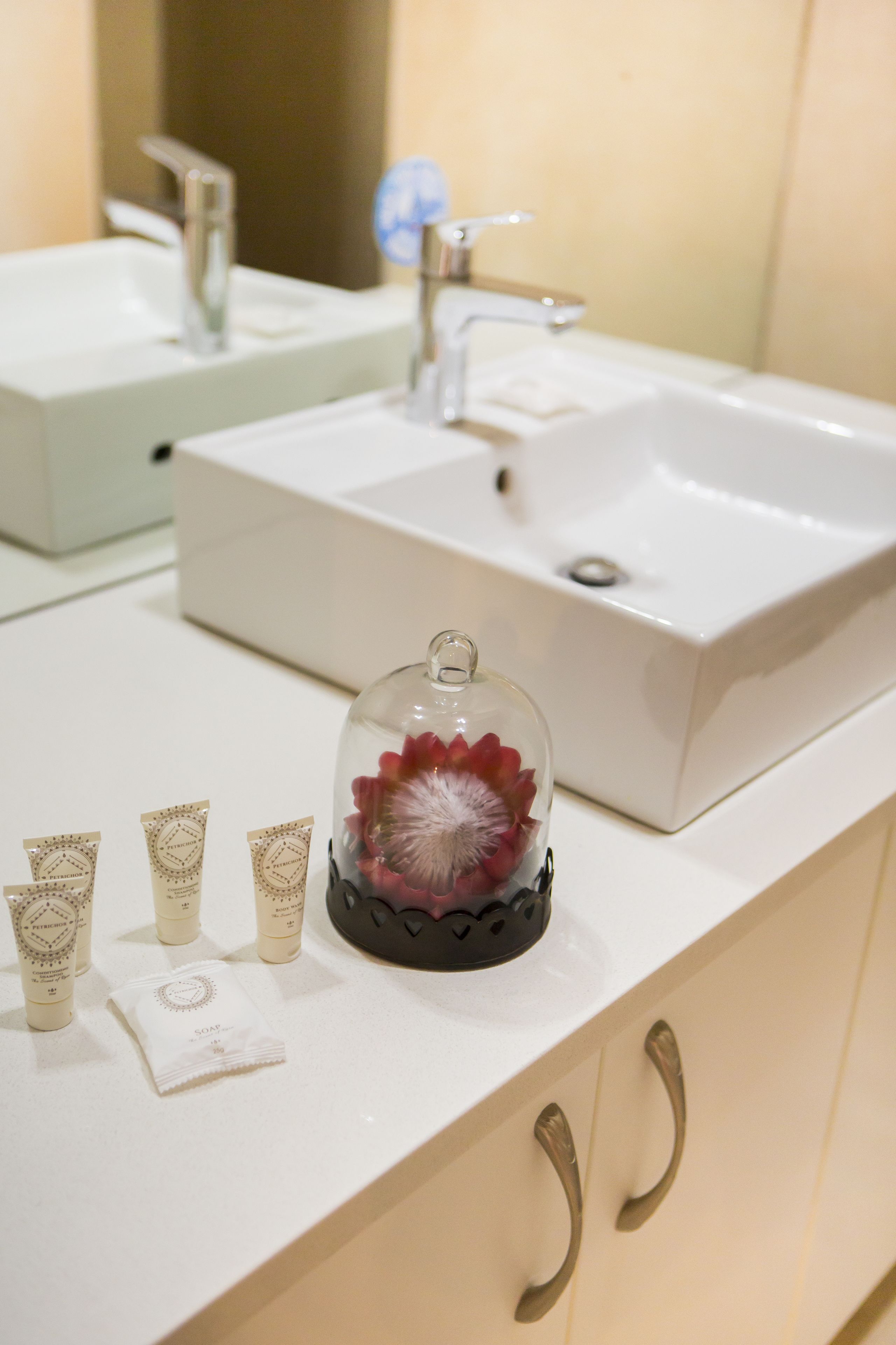 A bathroom with a white sink, a mirror, and toiletries on the counter.