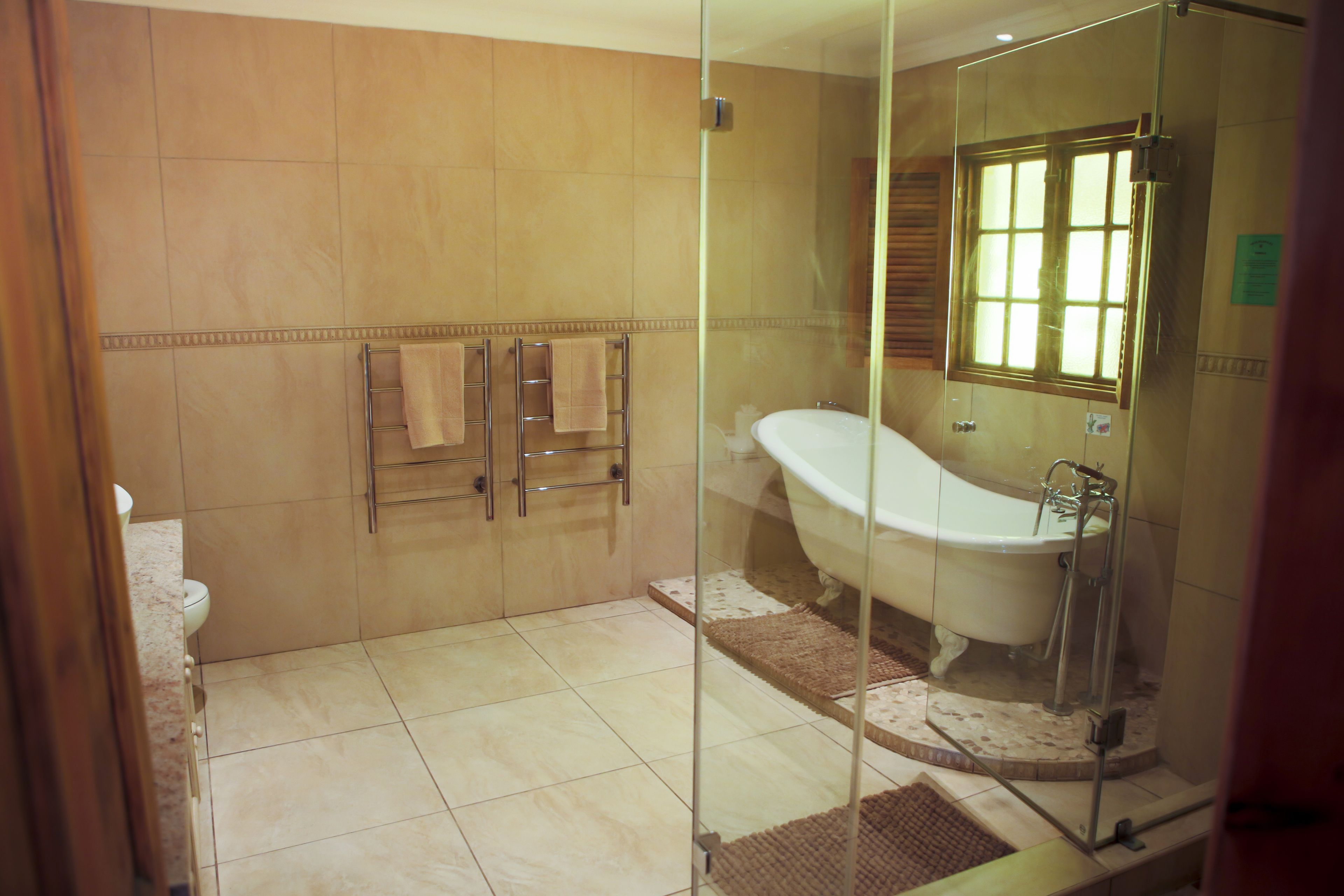 A bathroom with a glass-enclosed shower, a bathtub, and a toilet.