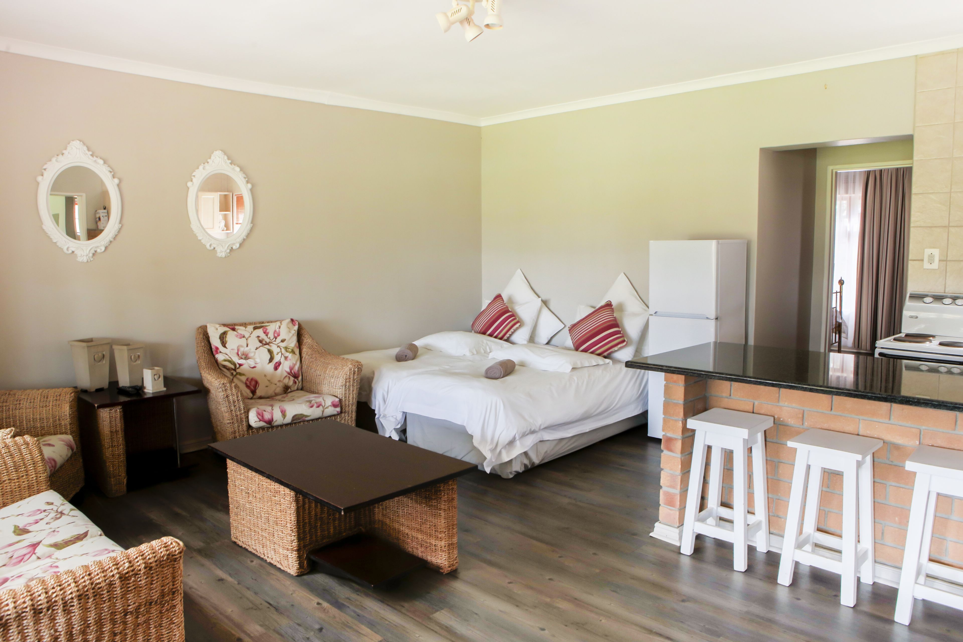 A compact living space with a bed, two chairs, a small table, and a kitchenette.