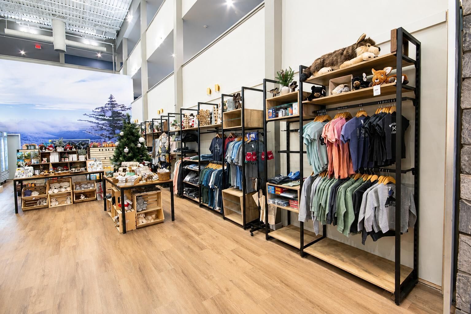 A clothing store with wooden flooring, metal shelving, and a Christmas tree.