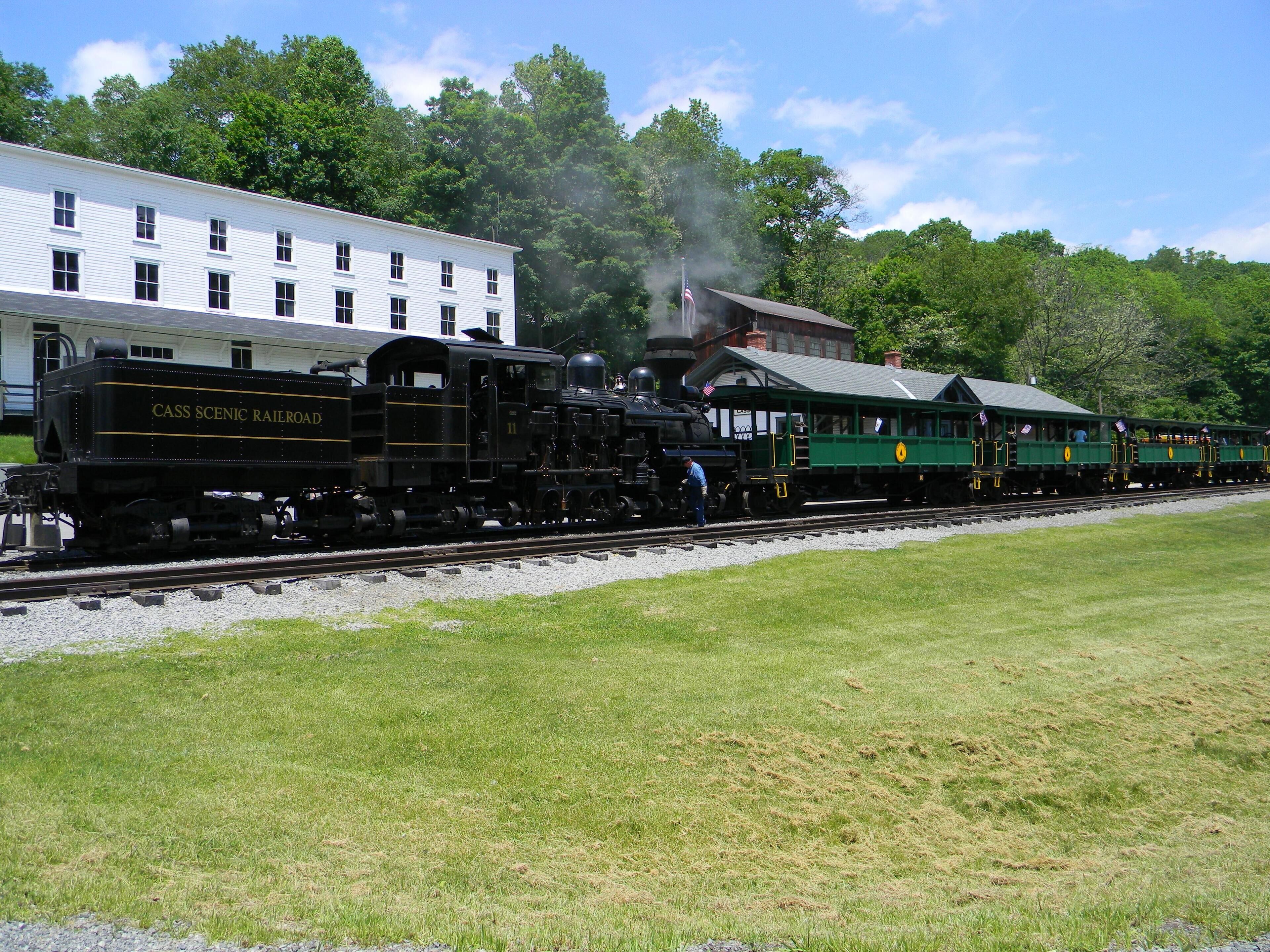 A black and green train with 'CASS SCENIC RAILROAD' written on it, moving along the tracks.