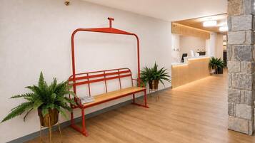 A reception area with a wooden bench, potted plants, and a reception desk.