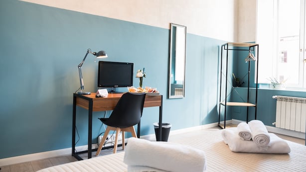 A bedroom with a desk, chair, computer, and a bed with rolled towels. - B&B  Lumiere Roma (Rome)