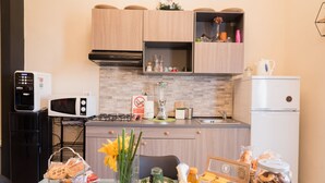 A modern kitchen with wooden cabinets, a microwave, a coffee machine, and a refrigerator. - B&B  Lumiere Roma (Rome)