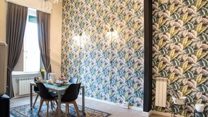 A dining area with a table set for four, a patterned wallpaper, and a radiator. - B&B  Lumiere Roma (Rome)