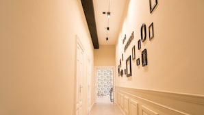 A hallway with a light-colored floor, white walls, and a patterned wallpaper at the end. - B&B  Lumiere Roma (Rome)