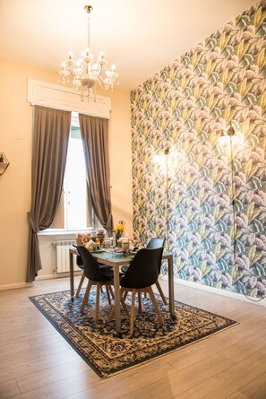 Comedor con una mesa dispuesta para cuatro personas, un candelabro y un papel tapiz estampado.