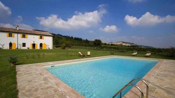 Relax by the serene pool surrounded by lush greenery and rolling hills.
