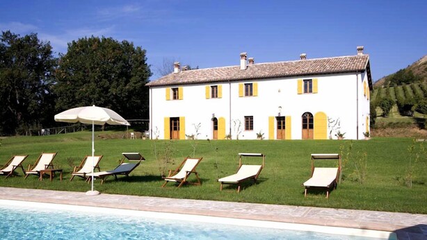 Un espace aménagé au bord de la piscine, avec des chaises longues et un parasol blanc.