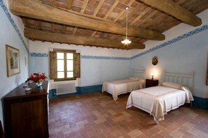 Une chambre avec deux lits simples, un plafond en bois, un radiateur et une fenêtre.