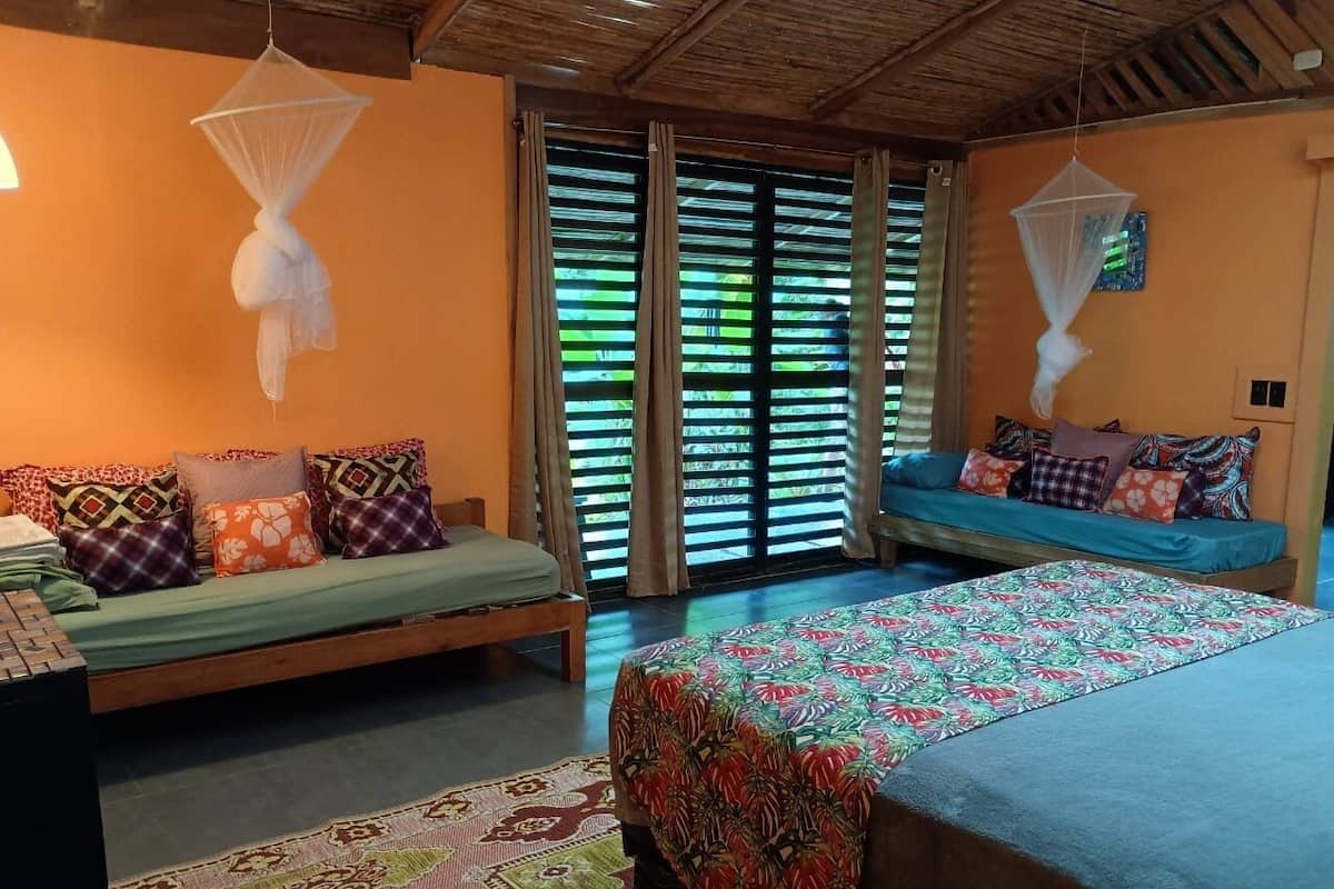 Una habitación con dos camas, un banco y una mosquitera.