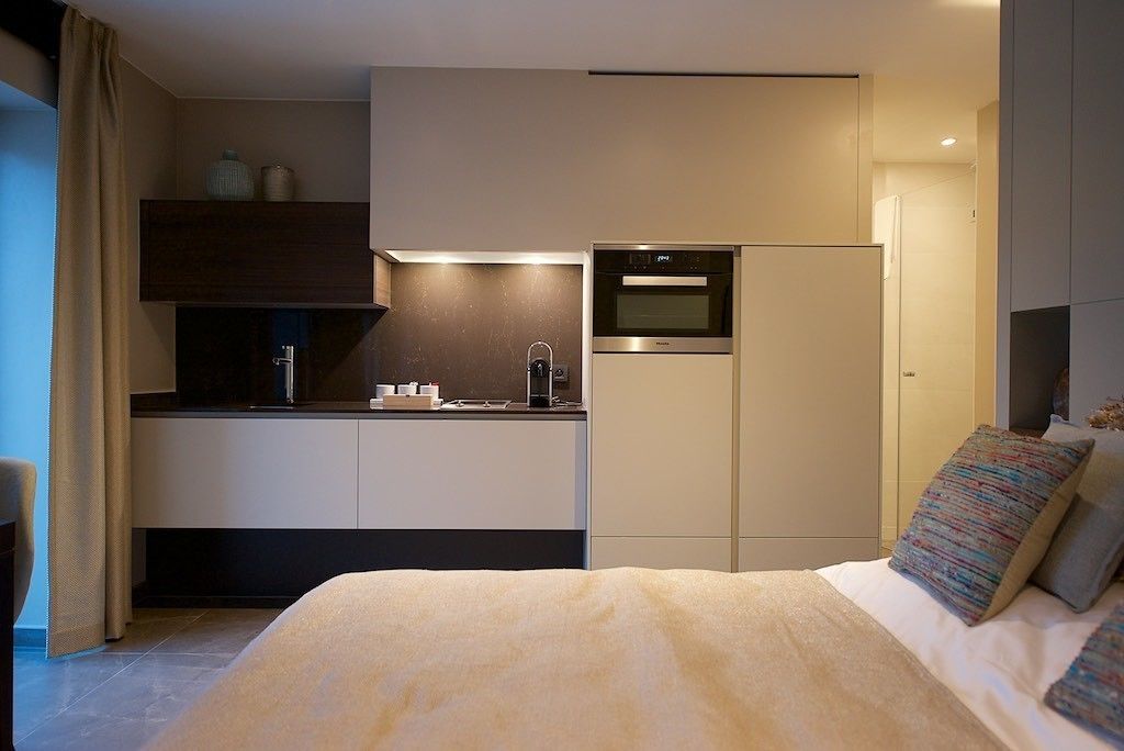 Une chambre d’hôtel compacte comprenant un lit, une kitchenette et un four encastré.