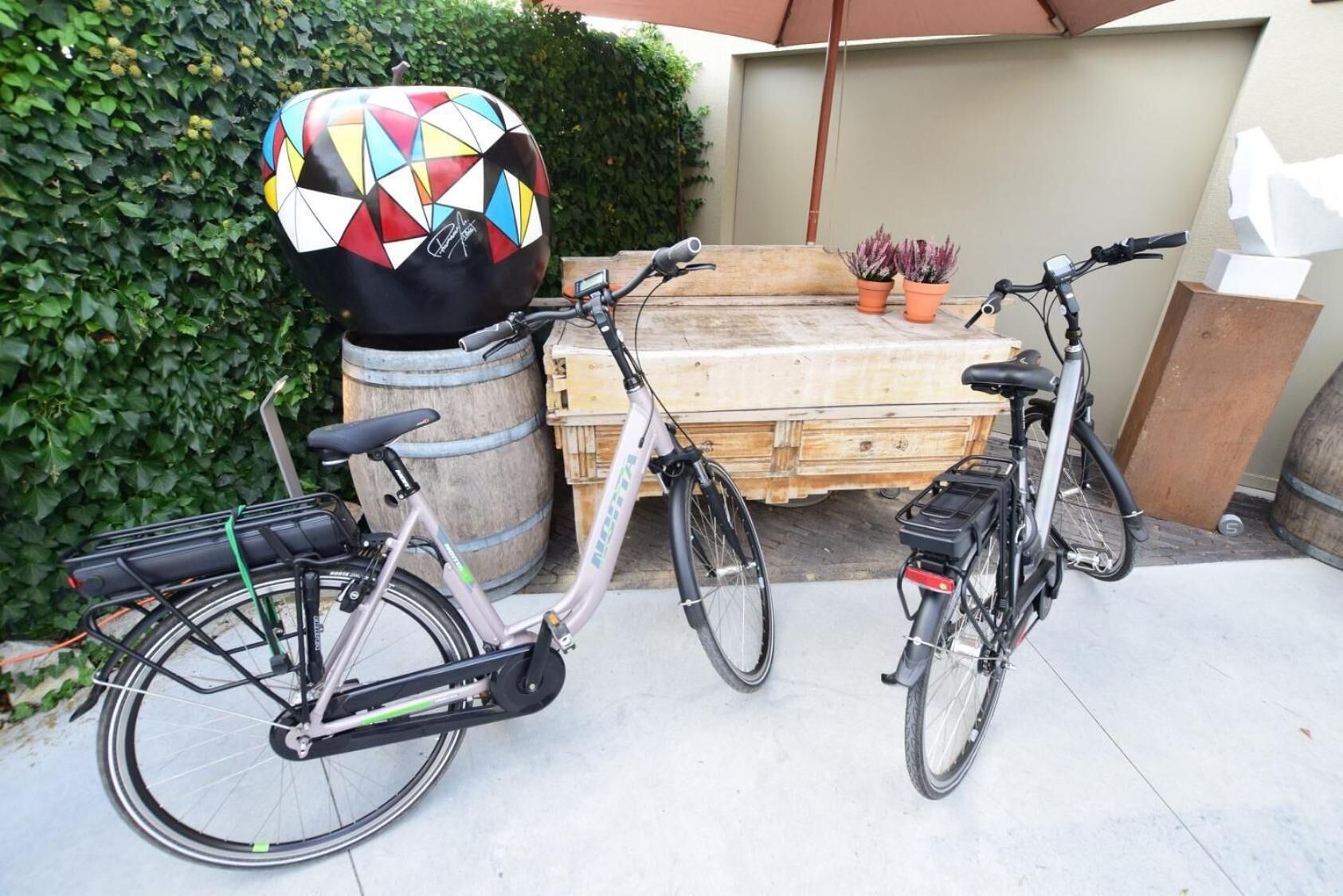 Dos bicicletas estacionadas frente a una mesa de madera con un casco colorido encima.