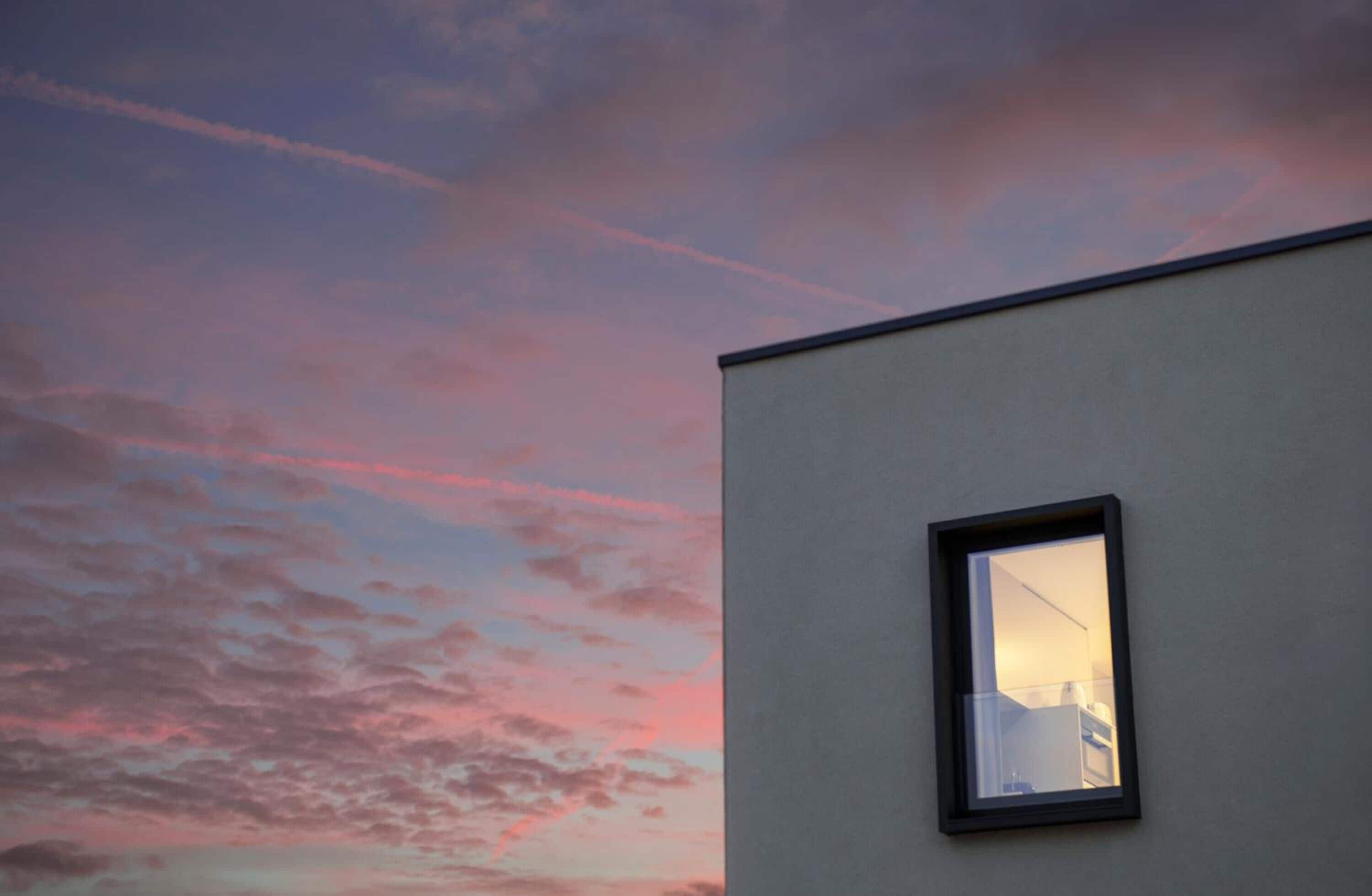 A building with a window reflecting a sunset sky.