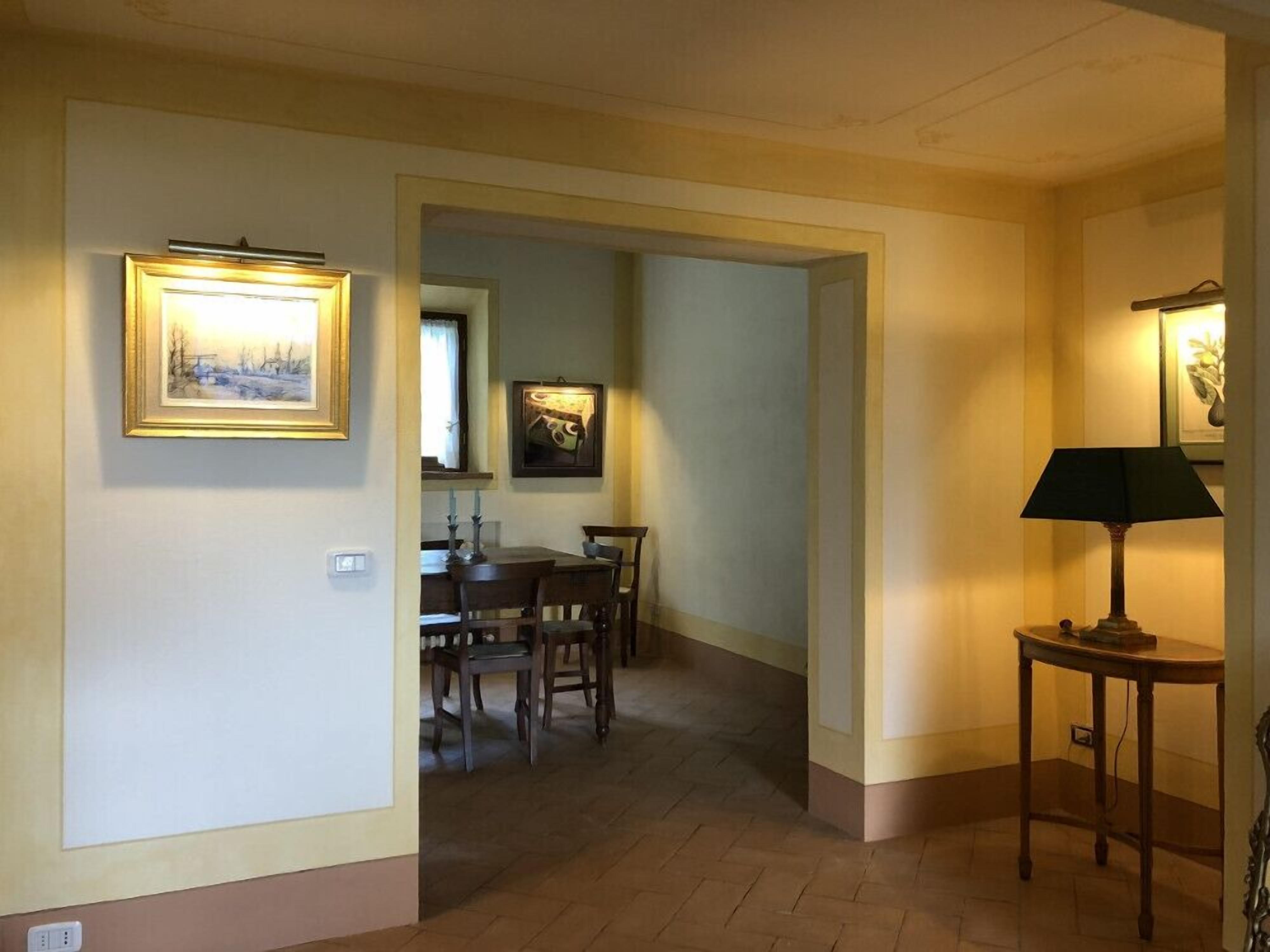Een gang met een eetgedeelte, met een tafel en stoelen, en twee wandlampen.