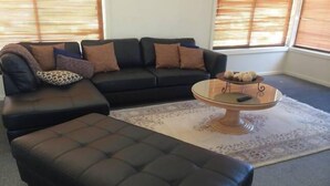Ein Wohnzimmer mit einer schwarzen Ledersofa, einem runden Couchtisch und einem gemusterten Teppich.