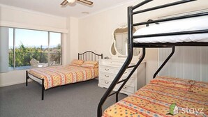 Ein Zimmer mit Etagenbetten, Deckenventilator, Fenster mit Blick und Kommode.