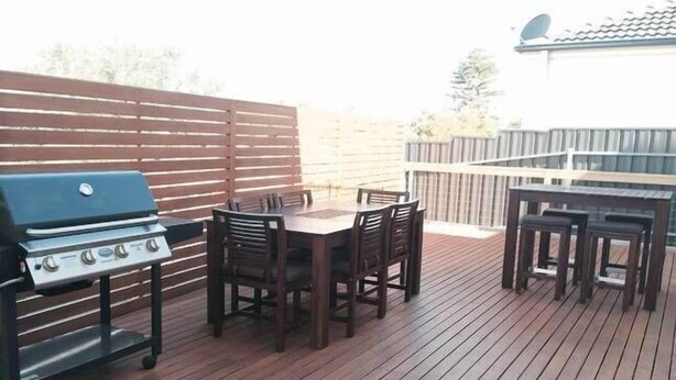 Eine Terrass mit Grill, Esstisch und Stühlen.