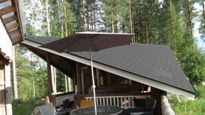 Une terrasse extérieure avec des meubles en osier et un grand parasol.