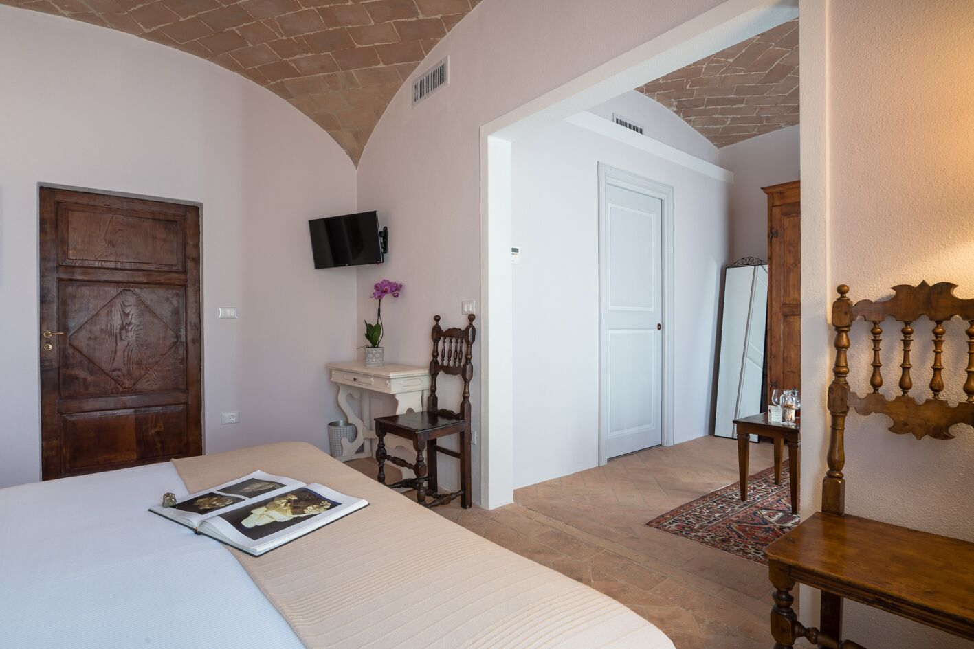 Un dormitorio con una cama, un escritorio con una silla, un televisor y una puerta.