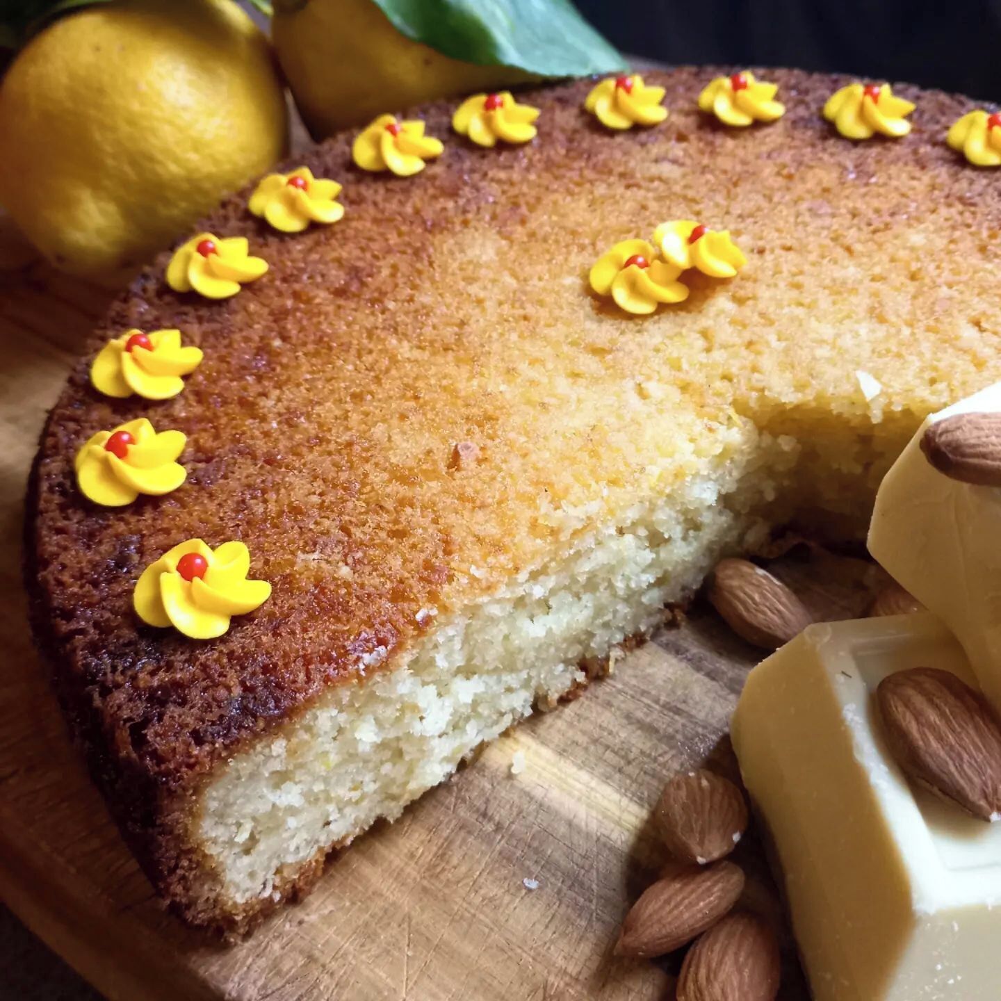 Un pastel con decoraciones de flores amarillas sobre una tabla de madera.