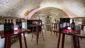 An underground wine cellar with wooden tables, wine bottles, and a piano. - Dimora delle Muse (Montalcino)