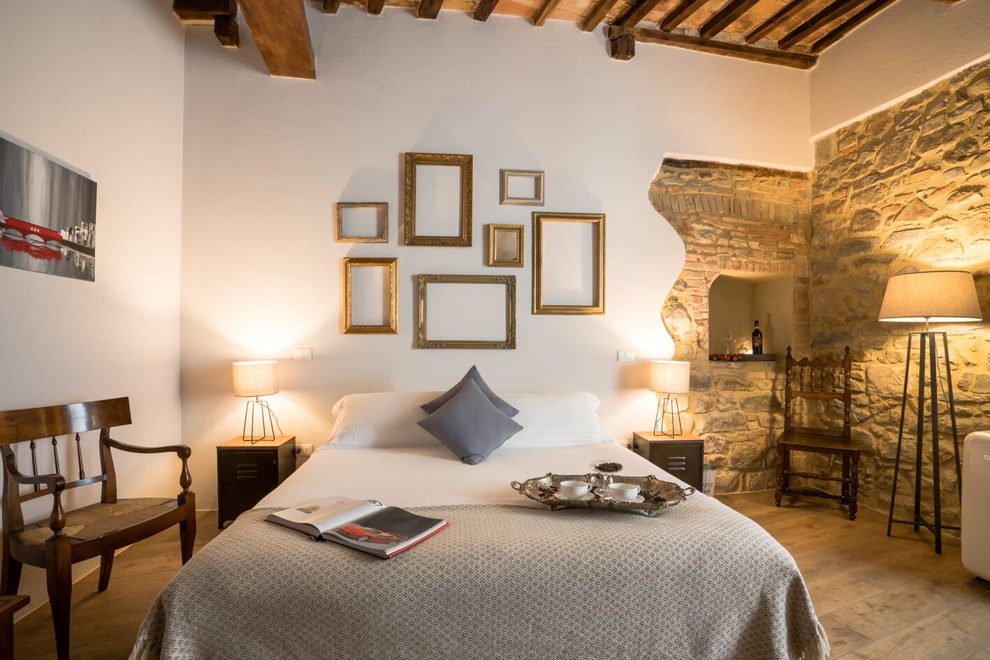 Un dormitorio acogedor con cama, lámpara de lectura, silla y pared de piedra.