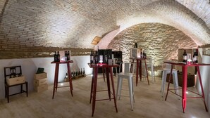 An underground wine cellar with brick walls, wooden tables, and chairs. - Dimora delle Muse (Montalcino)